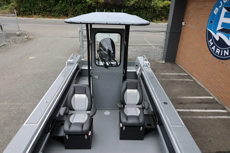 Slide: The Image of 2026 Thunder Jet 209 Rush Center Console boat with dual seats, parked near a marine shop. - 24