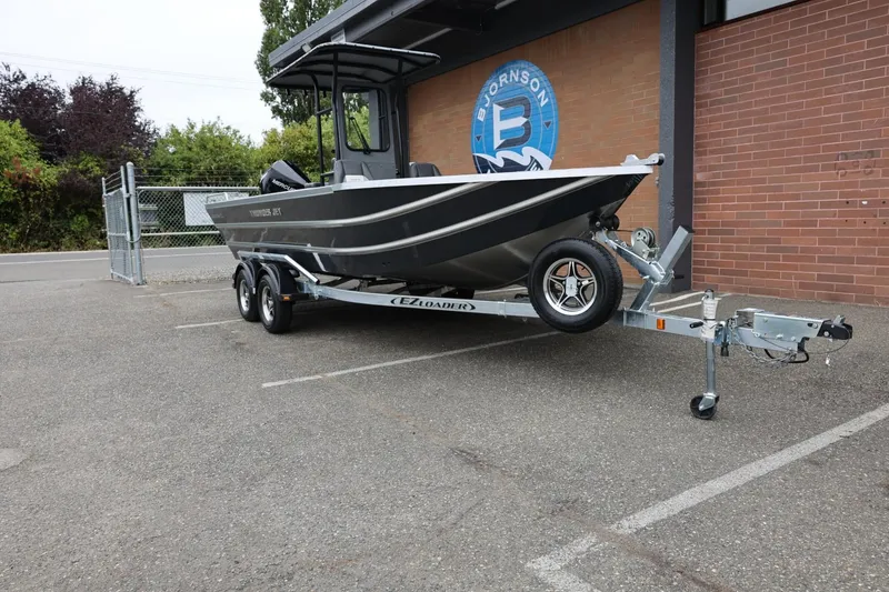 Slide: The Image of 2026 Thunder Jet 209 Rush Center Console boat on trailer, parked near brick building. - 3