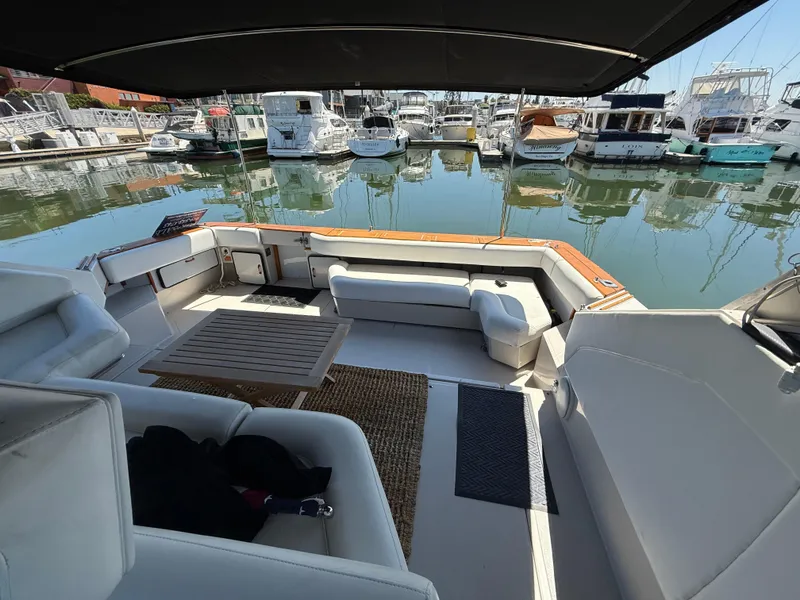 Slide: The Image of 1986 Sea Ray 460 Express Cruiser interior with seating and table, docked at marina. - 16