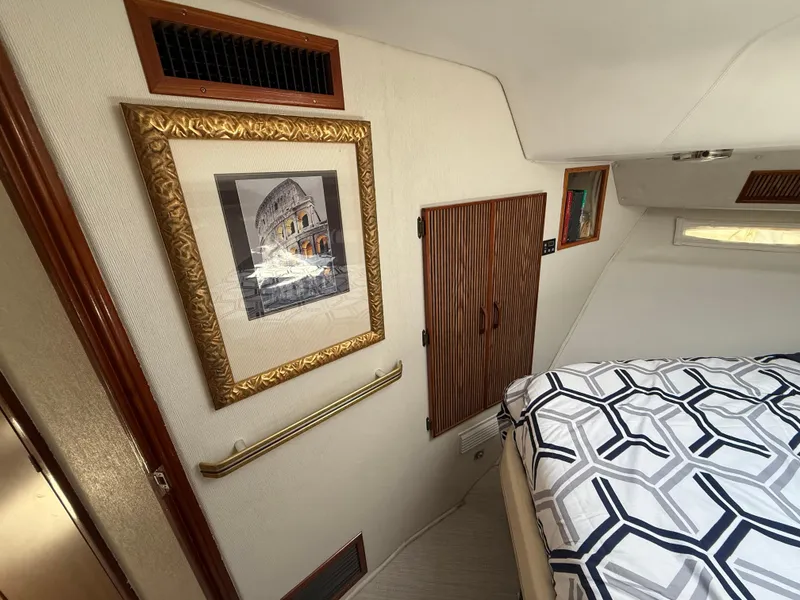 Slide: The Image of Interior of 1986 Sea Ray 460 Express Cruiser with framed artwork and patterned bedding. - 23