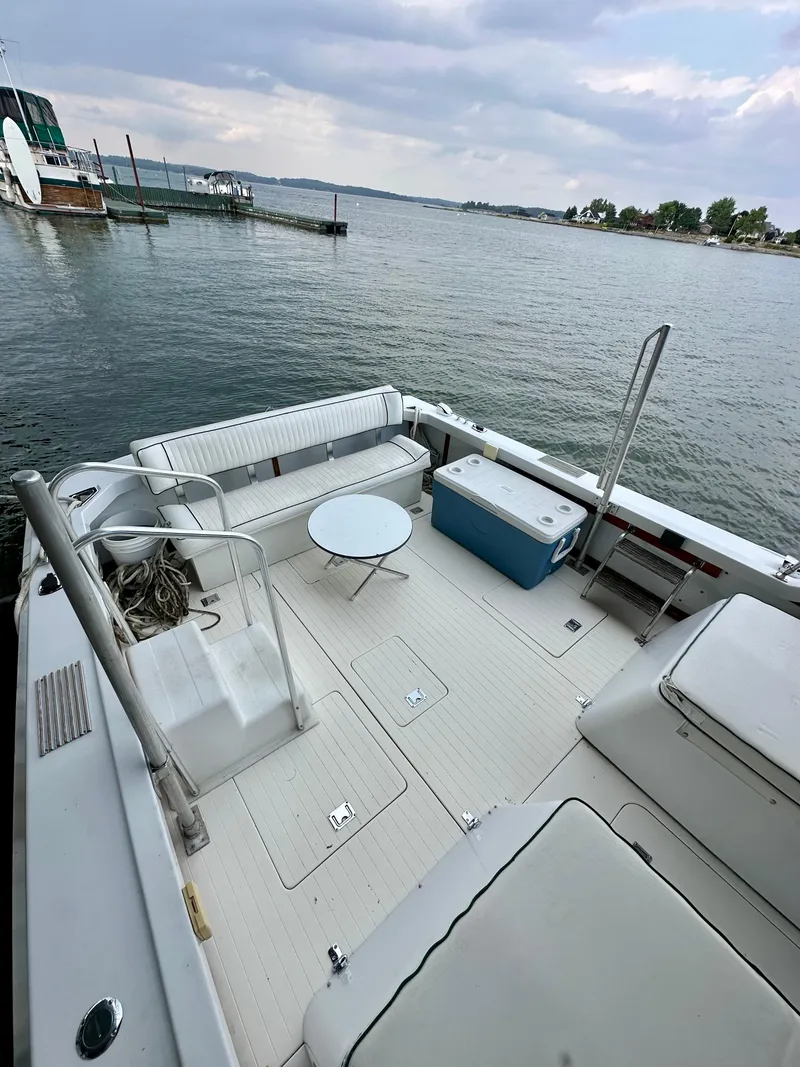 Slide: The Image of 1966 Bertram 31 Bahia Mar boat deck with seating, table, and cooler by the water. - 3