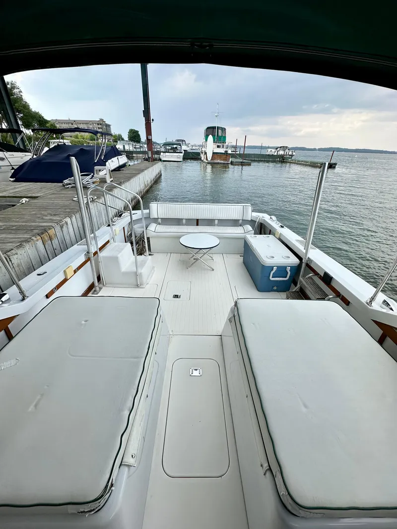 Slide: The Image of 1966 Bertram 31 Bahia Mar boat interior with seating and table, docked by the water. - 4