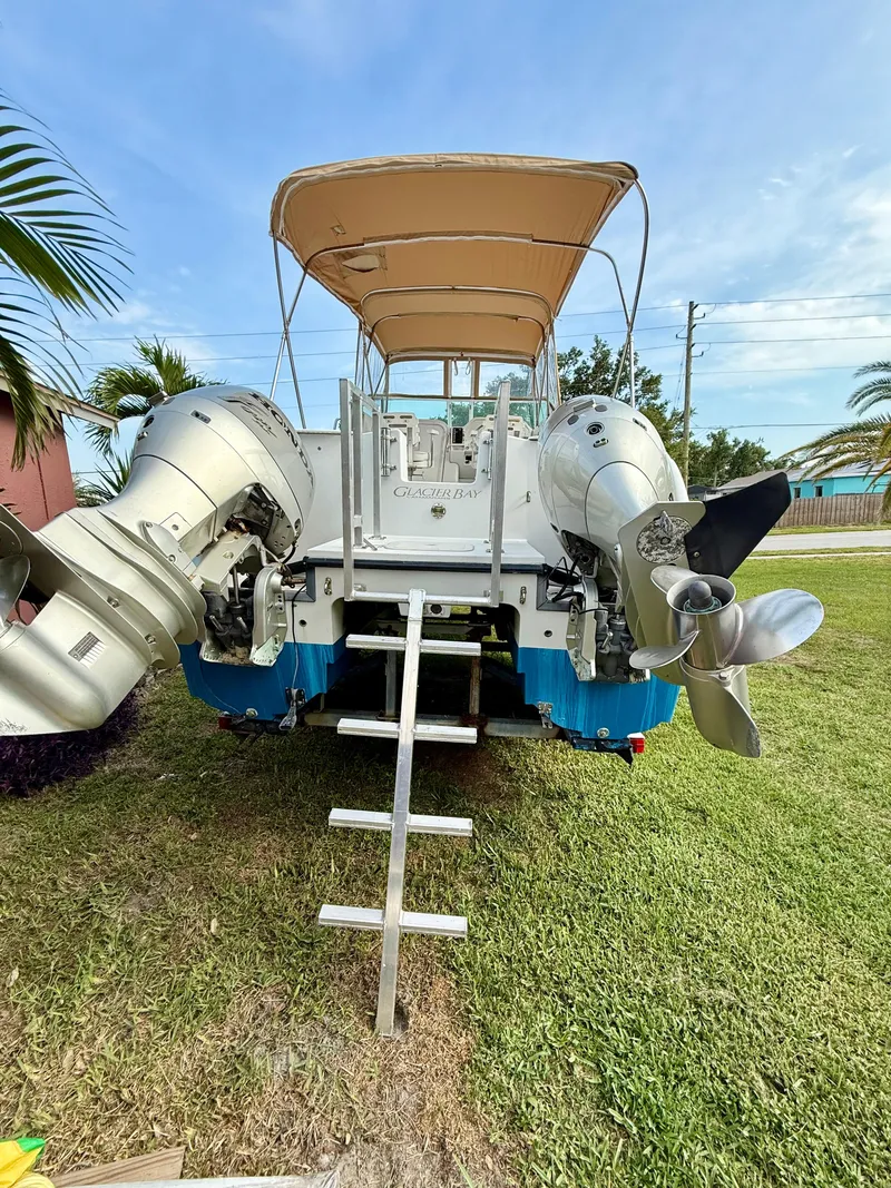Slide: The Image of 2002 Glacier Bay 2670 Island Runner boat with dual outboard motors and ladder on grass. - 4