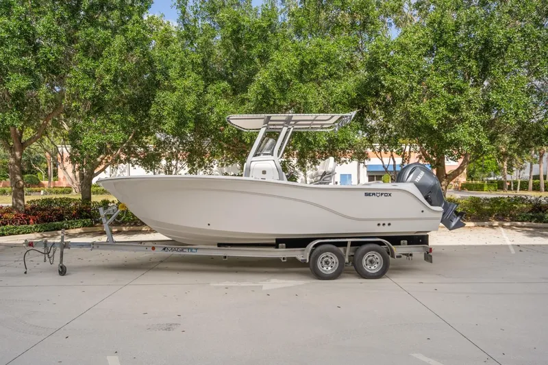 Slide: The Image of 2025 Sea Fox 228 Commander boat on trailer, parked outdoors with trees in background. - 0