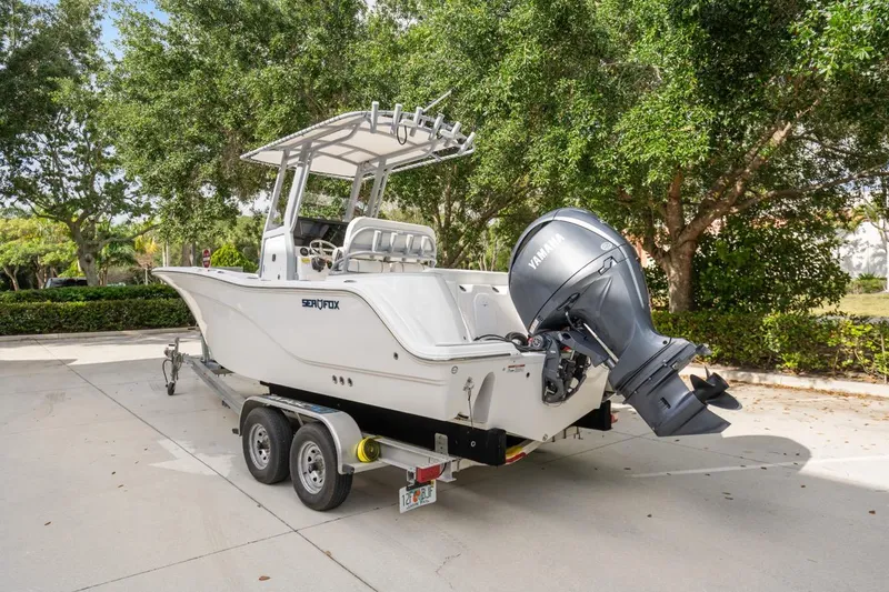 Slide: The Image of 2025 Sea Fox 228 Commander boat on trailer, parked outdoors with trees in background. - 1