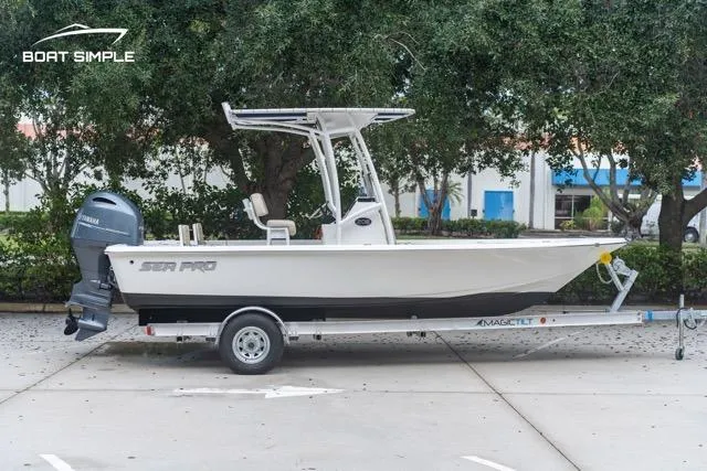 Slide: The Image of 2024 Sea Pro 208 Bay boat on trailer, parked outdoors with trees in background. - 3
