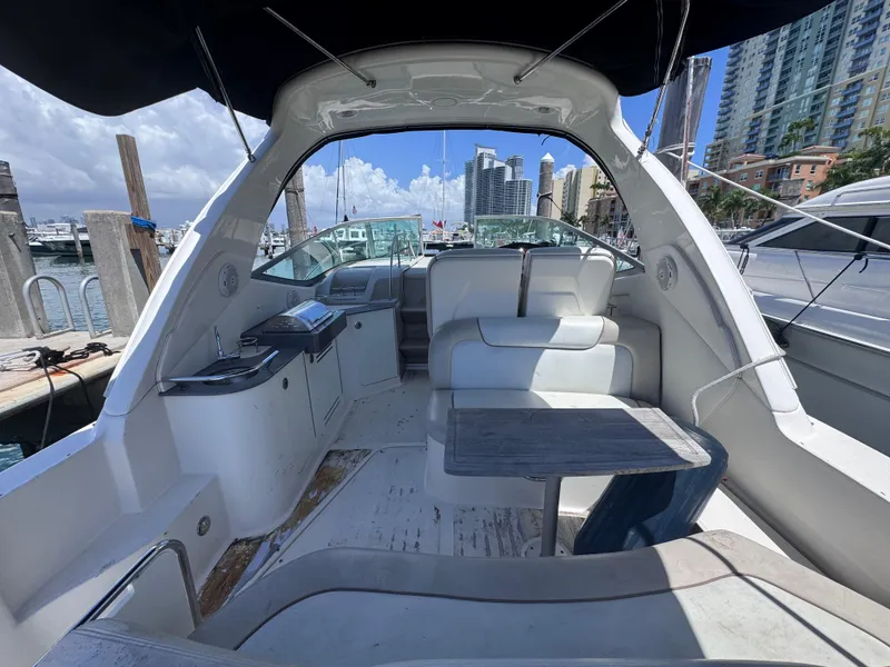 Slide: The Image of 2012 Sea Ray 330 Sundancer interior with seating and table, docked in a marina. - 13