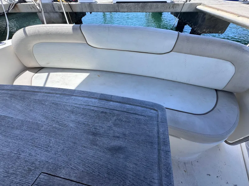 Slide: The Image of 2012 Sea Ray 330 Sundancer boat interior with cushioned seating and wooden table. - 16