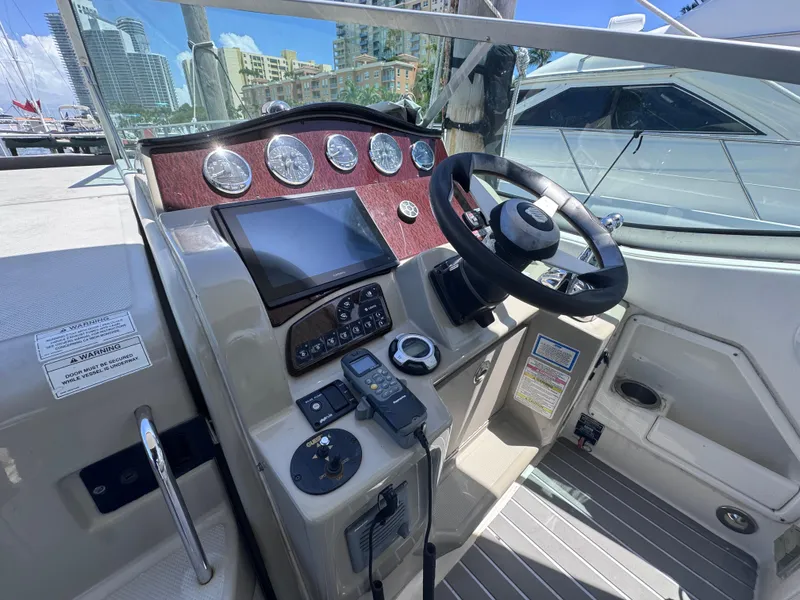 Slide: The Image of 2012 Sea Ray 330 Sundancer helm with steering wheel, gauges, and navigation equipment. - 21