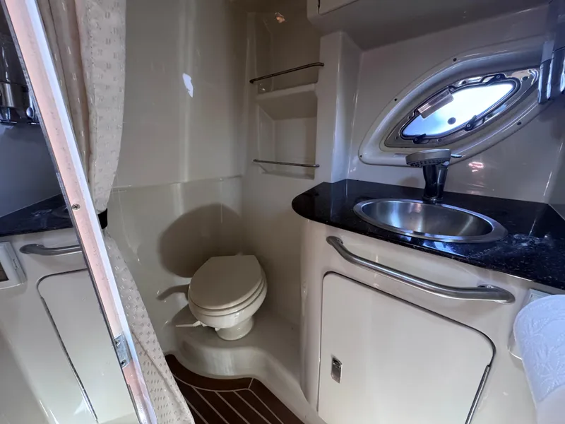 Slide: The Image of 2012 Sea Ray 330 Sundancer bathroom with toilet, sink, and porthole window. - 41
