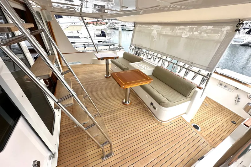 Slide: The Image of 2006 Grand Banks 72 Yachtfisher deck with seating, table, and ladder, docked at marina. - 12