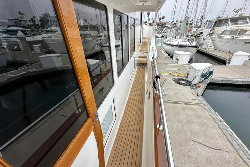 Slide: The Image of 2006 Grand Banks 72 Yachtfisher docked, showcasing sleek wooden deck and marina surroundings. - 24