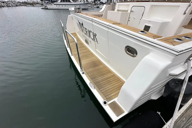 Slide: The Image of 2006 Grand Banks 72 Yachtfisher docked, showcasing elegant teak deck and sleek design. - 5
