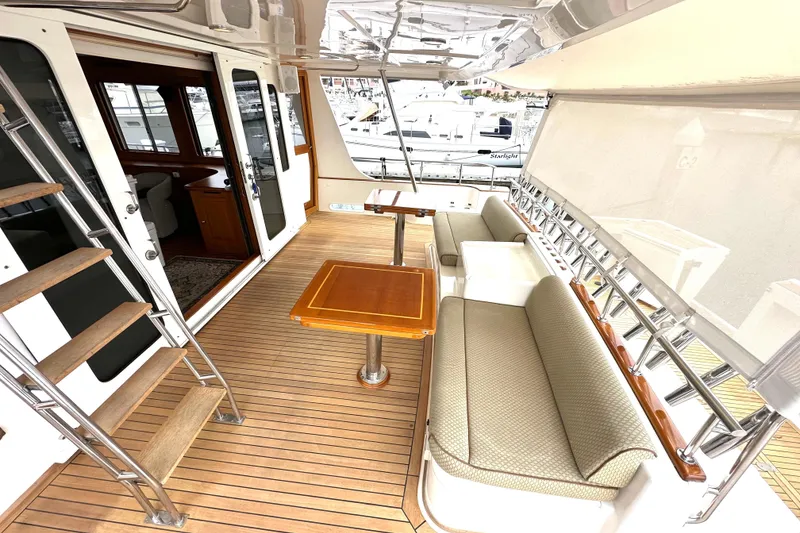 Slide: The Image of Luxurious 2006 Grand Banks 72 Yachtfisher deck with seating and wooden table. - 9