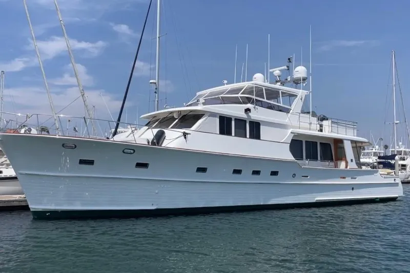 Slide: The Image of 2006 Grand Banks 72 Yachtfisher, elegant white yacht docked in marina under clear blue sky. - 1