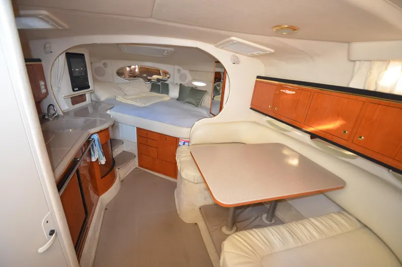 Slide: The Image of Interior of 2001 Sea Ray 310 Sundancer, featuring cozy seating, kitchenette, and sleeping area. - 18