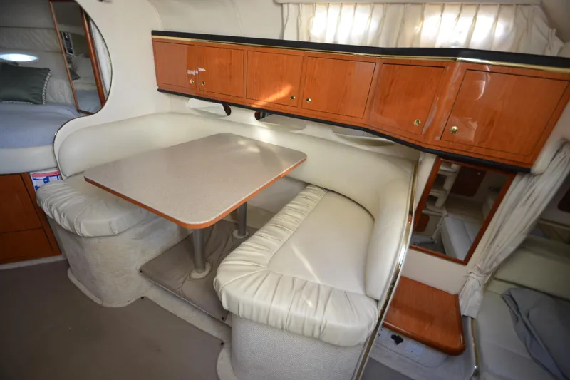 Slide: The Image of 2001 Sea Ray 310 Sundancer cabin with dining area, wooden cabinets, and plush seating. - 19