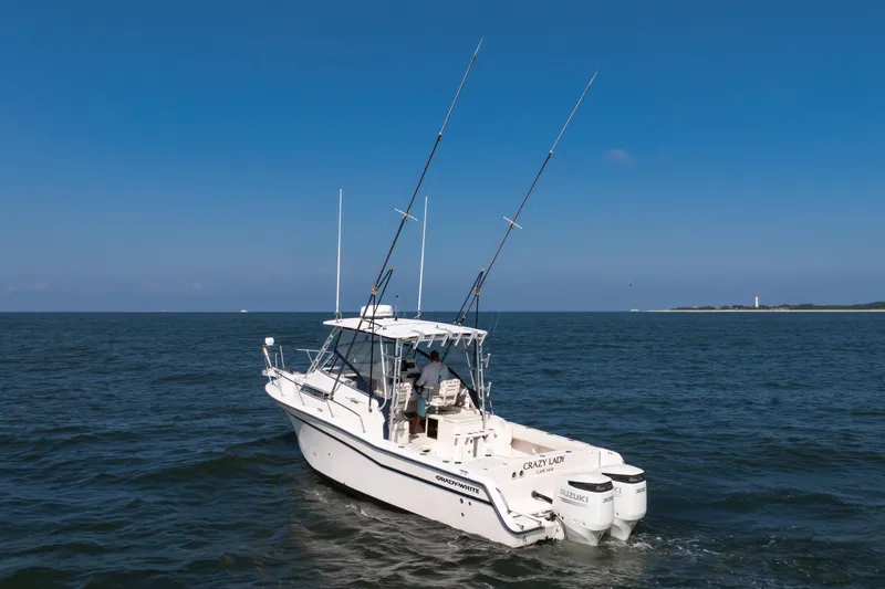 Slide: The Image of 1997 Grady-White Marlin 300 boat cruising on open water near coastline. - 12