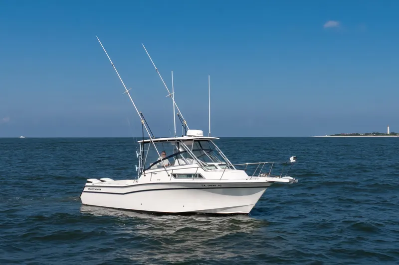 Slide: The Image of 1997 Grady-White Marlin 300 boat cruising on open water near coastline. - 19