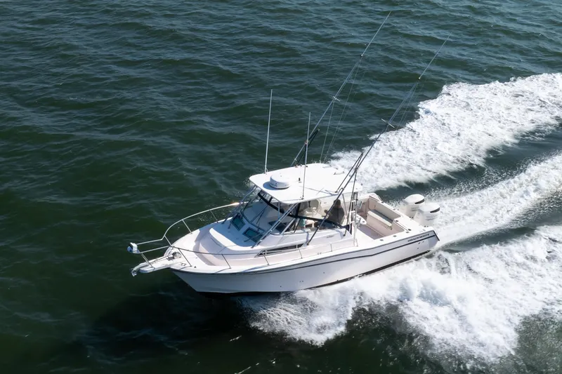 Slide: The Image of 1997 Grady-White Marlin 300 boat cruising on open water near a coastal town. - 28