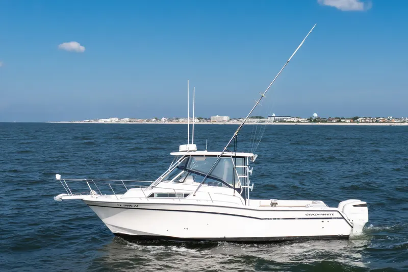 Slide: The Image of 1997 Grady-White Marlin 300 cruising on open water near a coastal town. - 4