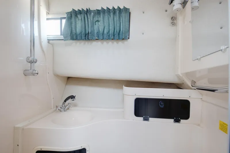 Slide: The Image of Interior of 1997 Grady-White Marlin 300 boat bathroom with sink and window curtain. - 64