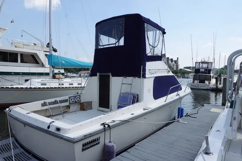 The Image of 1988 Pacemaker 308 boat docked at marina, featuring blue canopy and spacious deck. - 0