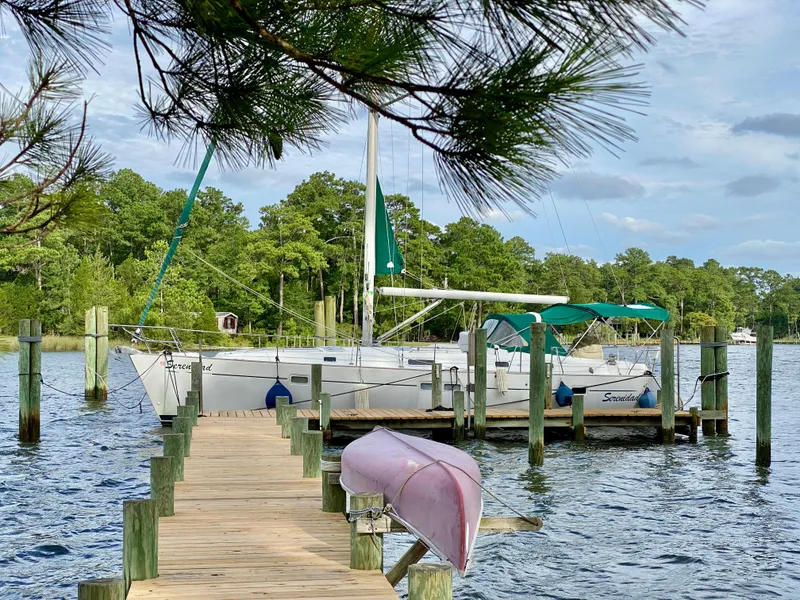 The Image of Sailboat Beneteau 411 (1999) docked by a wooden pier, surrounded by lush greenery. - 1