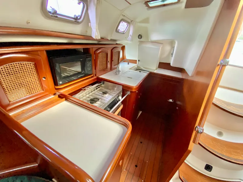 Slide: The Image of Interior of a 1999 Beneteau 411 sailboat kitchen with wood finish and appliances. - 18