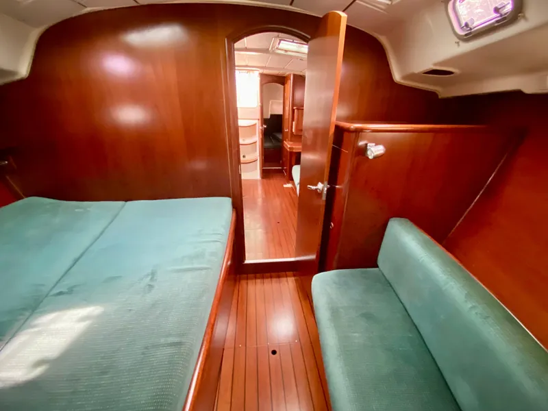 Slide: The Image of Interior of 1999 Beneteau 411 sailboat with wooden finish and green upholstery. - 26