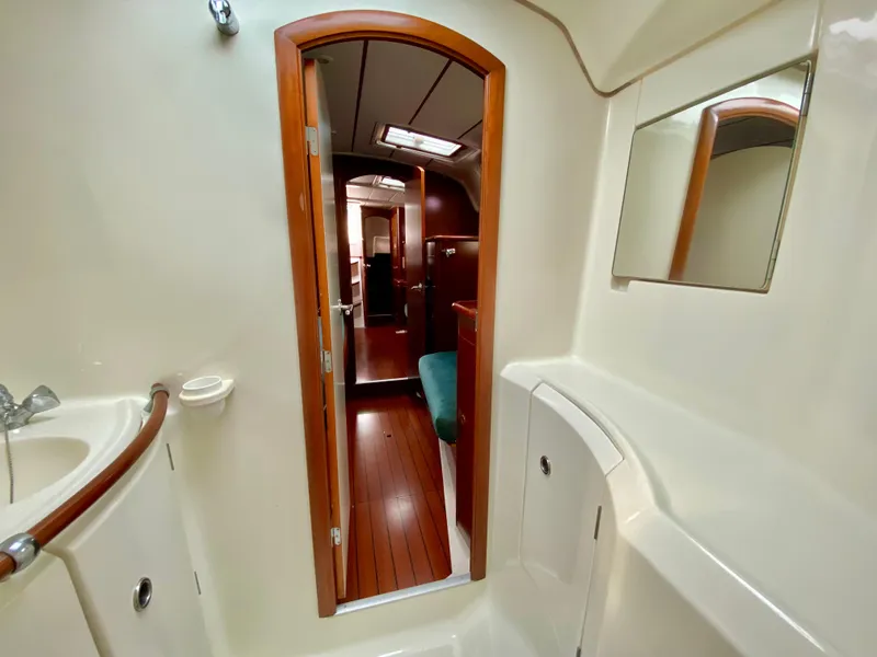 Slide: The Image of Interior of 1999 Beneteau 411 sailboat, featuring a bathroom with wooden accents and mirror. - 27