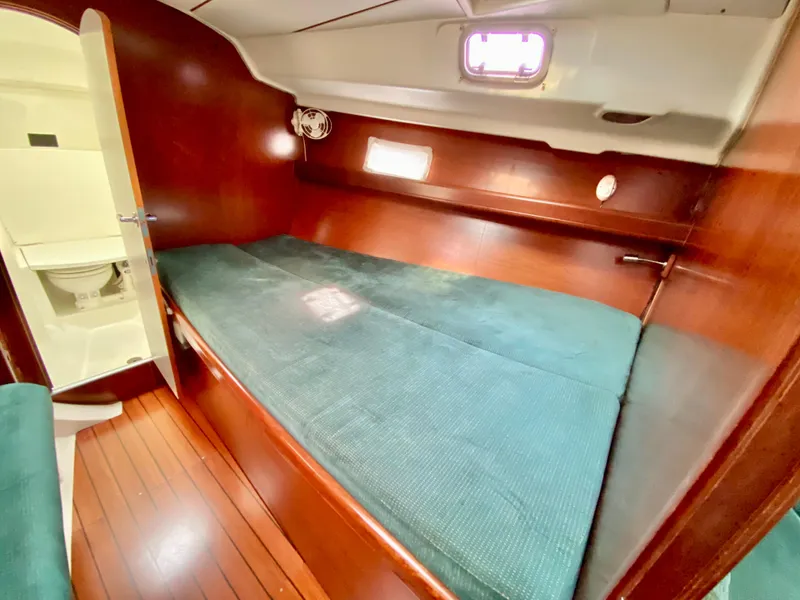Slide: The Image of Cozy cabin interior of 1999 Beneteau 411 sailboat with wooden finish and green bedding. - 29
