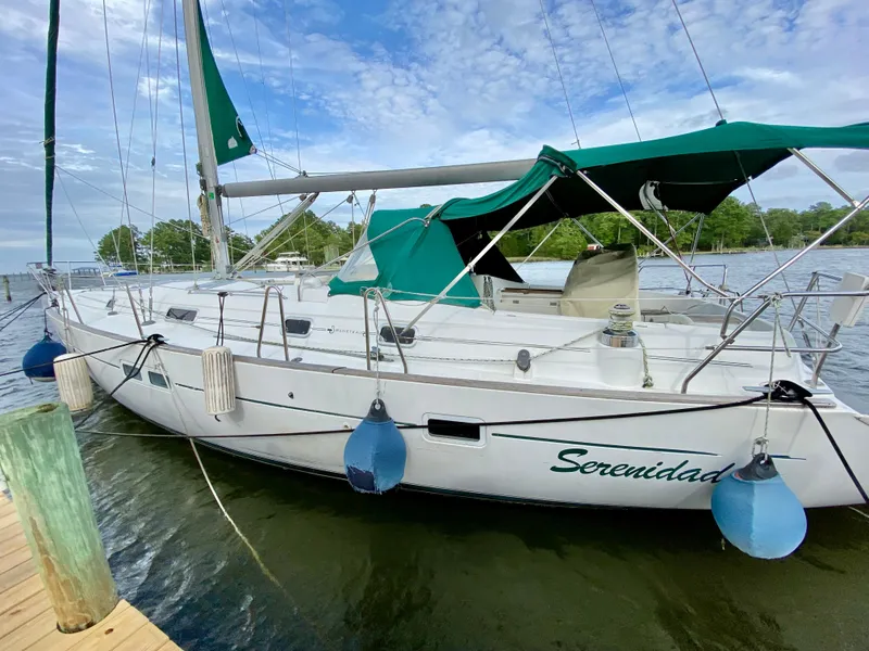 Slide: The Image of 1999 Beneteau 411 sailboat docked, featuring green canopy and serene waterscape. - 3