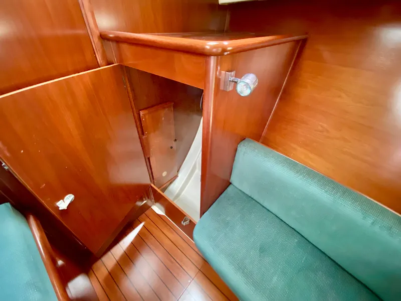Slide: The Image of Interior of 1999 Beneteau 411 sailboat with wooden cabinetry and green seating. - 31