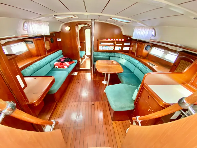 Slide: The Image of Interior of 1999 Beneteau 411 sailboat with wooden finish and green seating. - 33