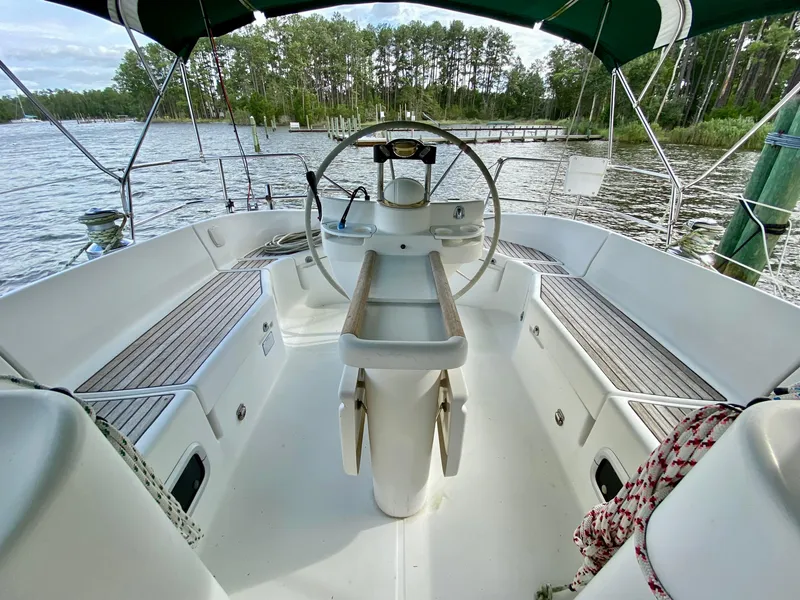 Slide: The Image of Cockpit of 1999 Beneteau 411 sailboat with steering wheel, docked by a scenic lake. - 9