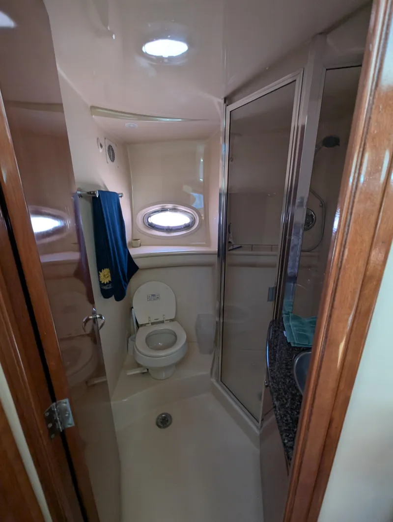 Slide: The Image of Compact bathroom in a 2006 Meridian 368 yacht, featuring a toilet, shower, and porthole window. - 12