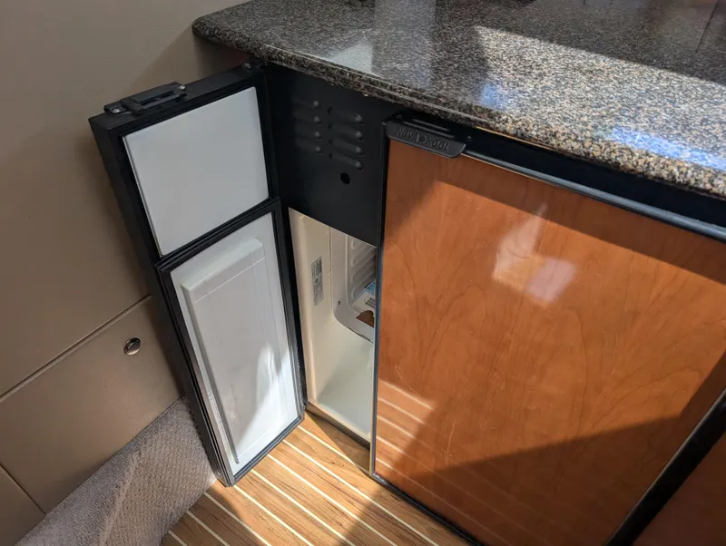 Slide: The Image of Compact refrigerator in 2006 Meridian 368 yacht interior, featuring wood paneling and granite countertop. - 8