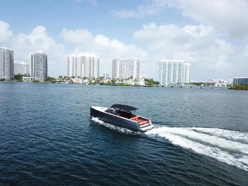 Slide: The Image of VanDutch 30 yacht cruising on water with city skyline in background, 2016 model. - 11