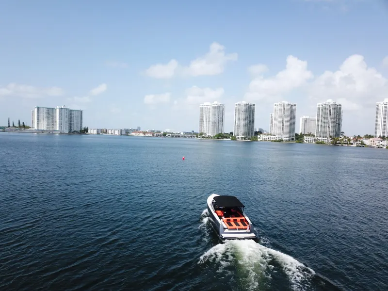 Slide: The Image of VanDutch 30 boat cruising on a sunny day with city skyline in the background. - 12