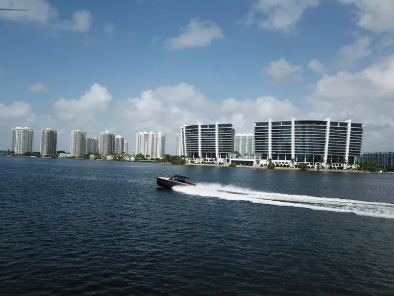 Slide: The Image of VanDutch 30 boat cruising on water with city skyline in background, 2016 model. - 14