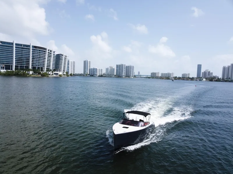 Slide: The Image of VanDutch 30 boat cruising on water with city skyline in background, 2016 model. - 9