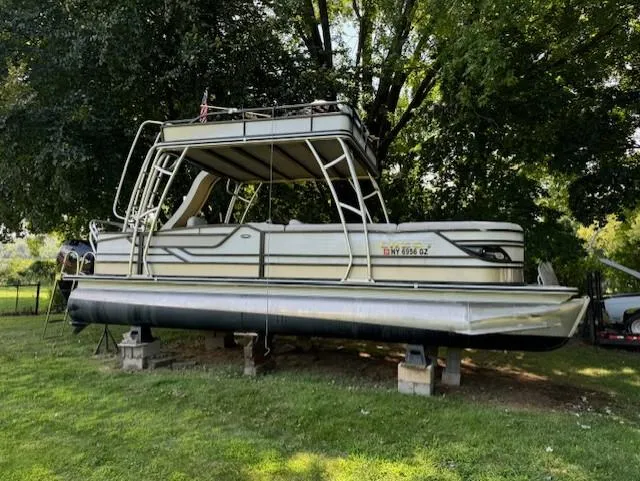 Slide: The Image of 2017 Crest Caribbean 250 L pontoon boat on blocks under trees. - 0