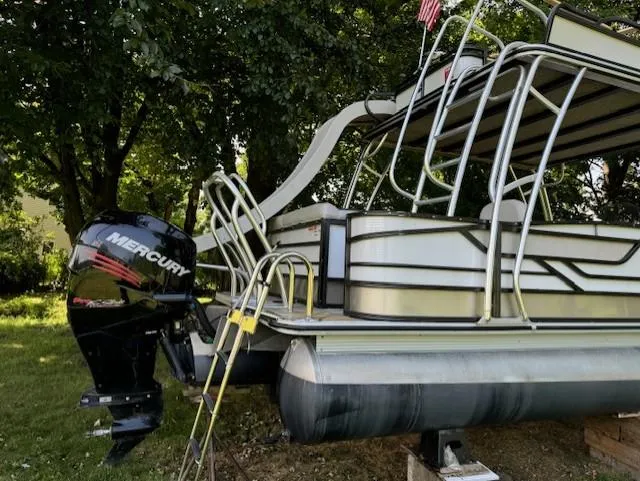Slide: The Image of 2017 Crest Caribbean 250 L pontoon boat with Mercury outboard motor, parked on grass. - 1