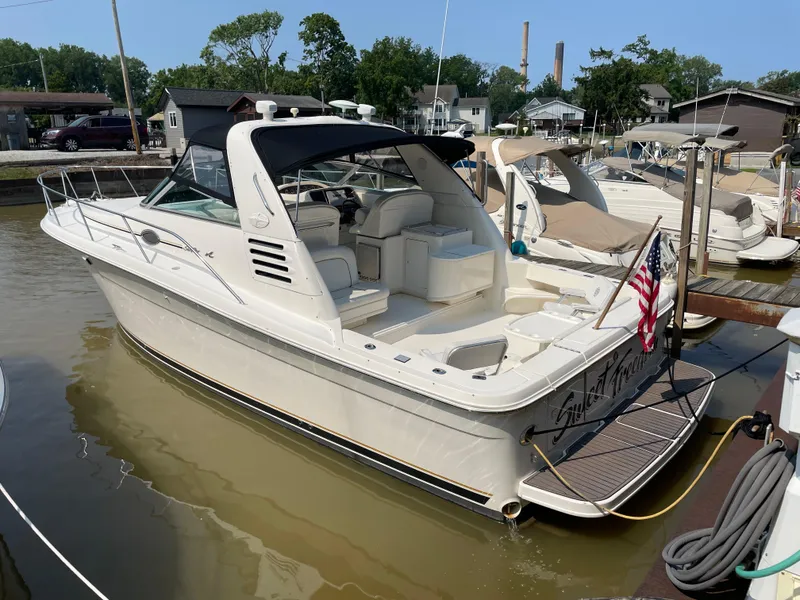 The Image of 1997 Sea Ray 330 Express docked at marina, featuring spacious deck and American flag. - 1