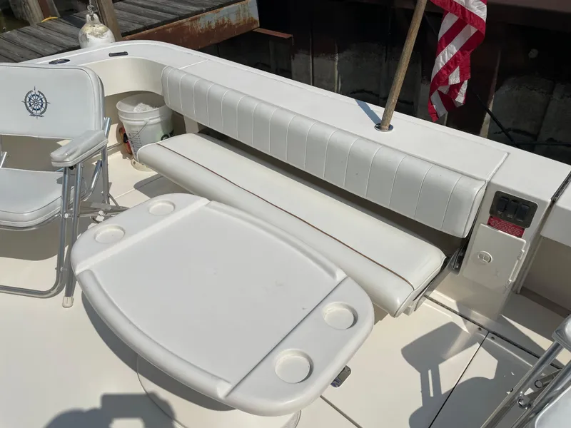 Slide: The Image of 1997 Sea Ray 330 Express boat interior with white seating and table, docked with American flag. - 13
