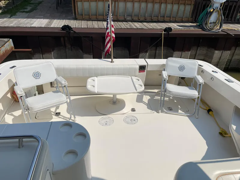 Slide: The Image of 1997 Sea Ray 330 Express boat deck with chairs and table, docked with American flag. - 19