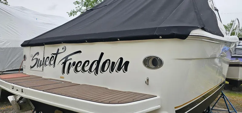 Slide: The Image of 1997 Sea Ray 330 Express boat named "Sweet Freedom" with black cover and wooden deck. - 44