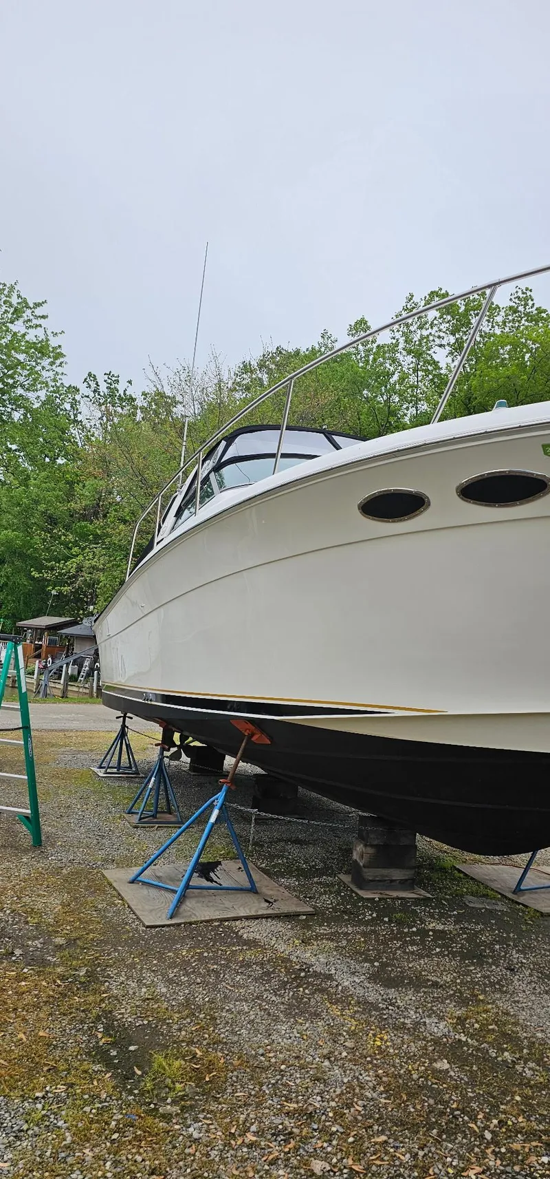 Slide: The Image of 1997 Sea Ray 330 Express boat on stands, surrounded by trees. - 47