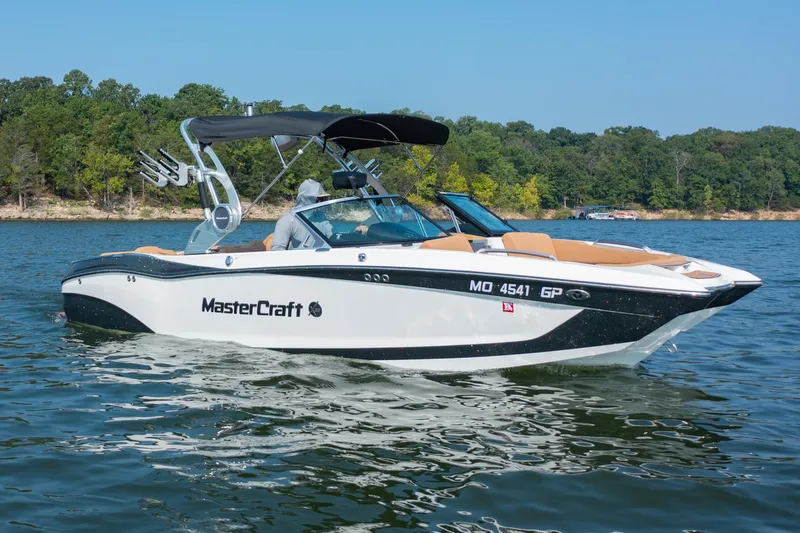 Slide: The Image of 2021 MasterCraft X22 boat on a lake with lush green shoreline. - 1